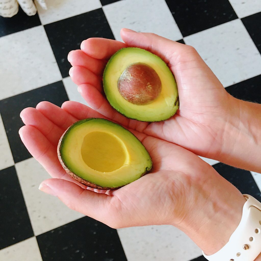 Photo of person holding an avocado cut in half symbolizing our fresh food options in our new home