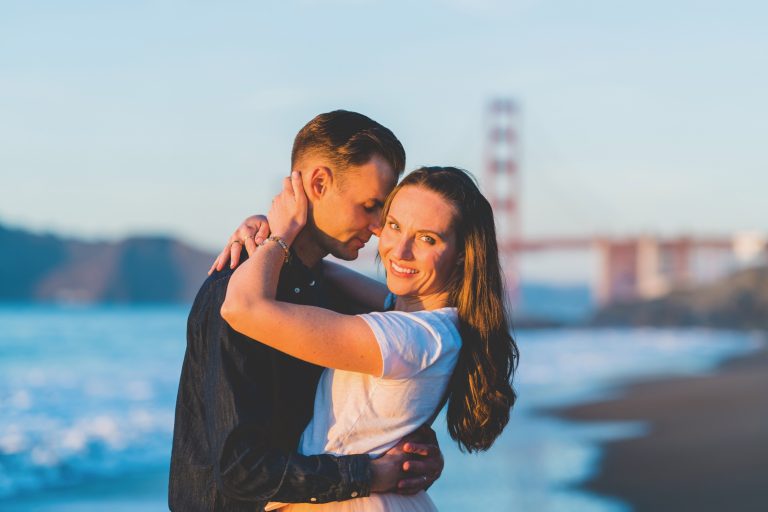 Greg Giunto & Misty Giunto caressing in front of the Golden Gate Bridge